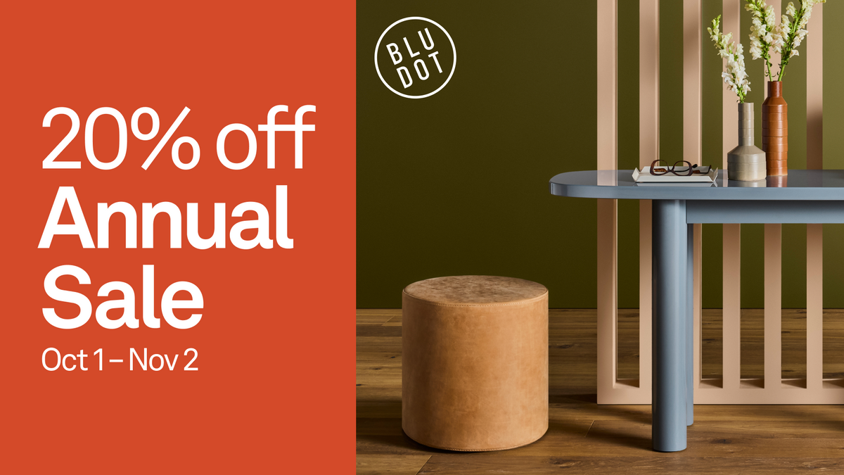 Promotional sale graphic for BLU DOT featuring a 20% off Annual Sale date Oct 1 - Nov 2 in white text on an orange-red block, next to a styled interior scene with a blue table, beige stool, olive green wall, and decorative vases.
