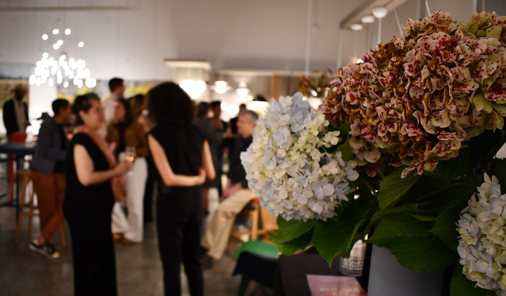 A photograph from Illuminee's Pale Rose Event in October 2023. Depicted are guests at the furniture showroom, with a focus point on a bouquet of flowers.