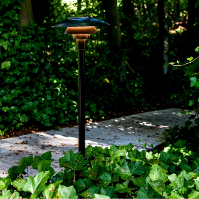 The PH 3-2½ Bollard from Louis Poulsen in a garden.