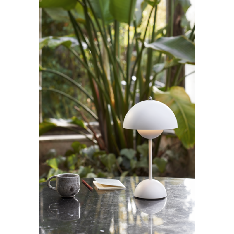 The Flowerpot VP9 Portable Table Lamp from &Tradition in a garden.