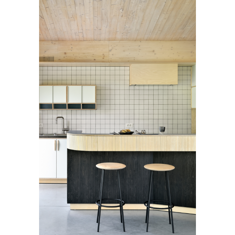 The Baretto Bar Stool from Ethnicraft in a kitchen area beneath the bar counter.