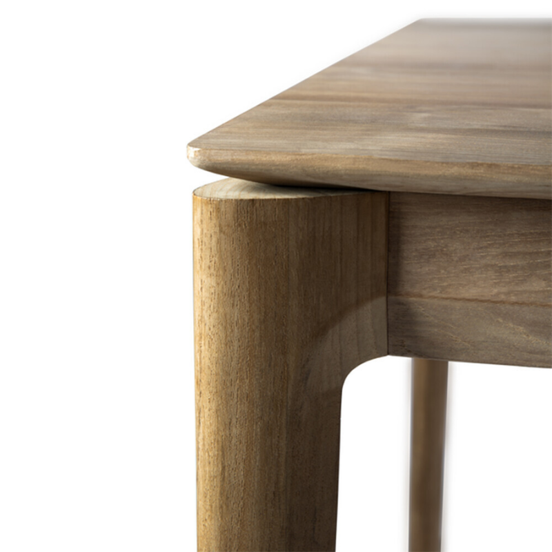 The Bok Dining Table from Ethnicraft in teak, in a close up shot showing the natural texture of the teak.