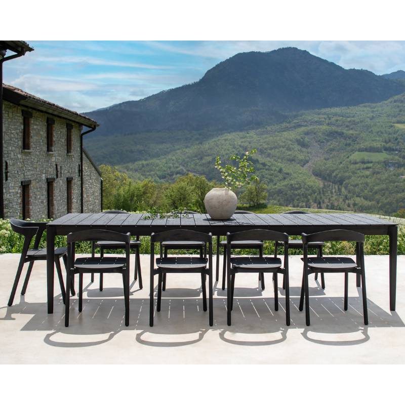 The Bok Outdoor Dining Chair from Ethnicraft outdoors with a mountain view in the background.