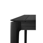 The Bok Outdoor Dining Table from Ethnicraft in solid teak tainted black, with a close up on the corner.