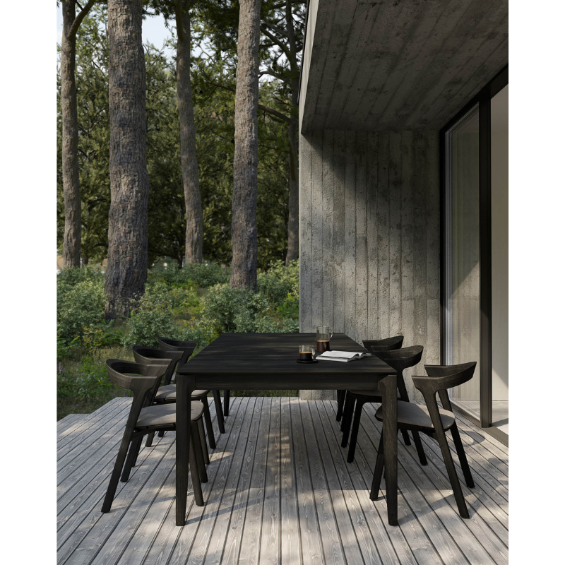 The Bok Outdoor Dining Table from Ethnicraft on a porch outdoors.