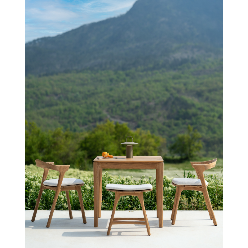 The Bok Outdoor Dining Table from Ethnicraft outdoors in a scenic lifestyle shot.