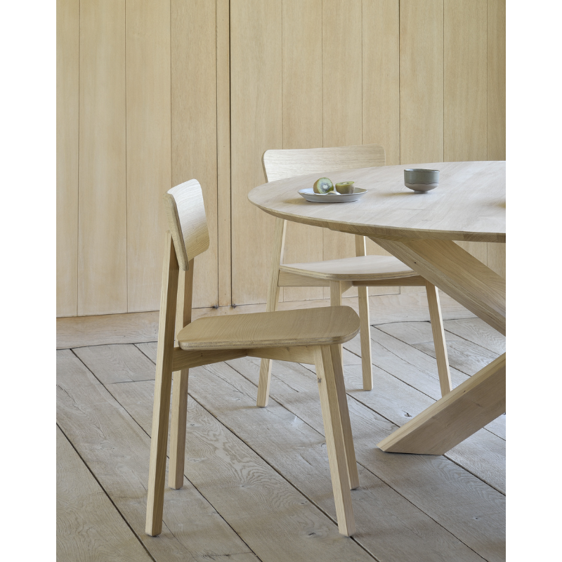 The Casale Dining Chair from Ethnicraft next to a dining table.