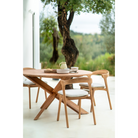The Circle Outdoor Dining Table from Ethnicraft outdoors overlooking a garden.
