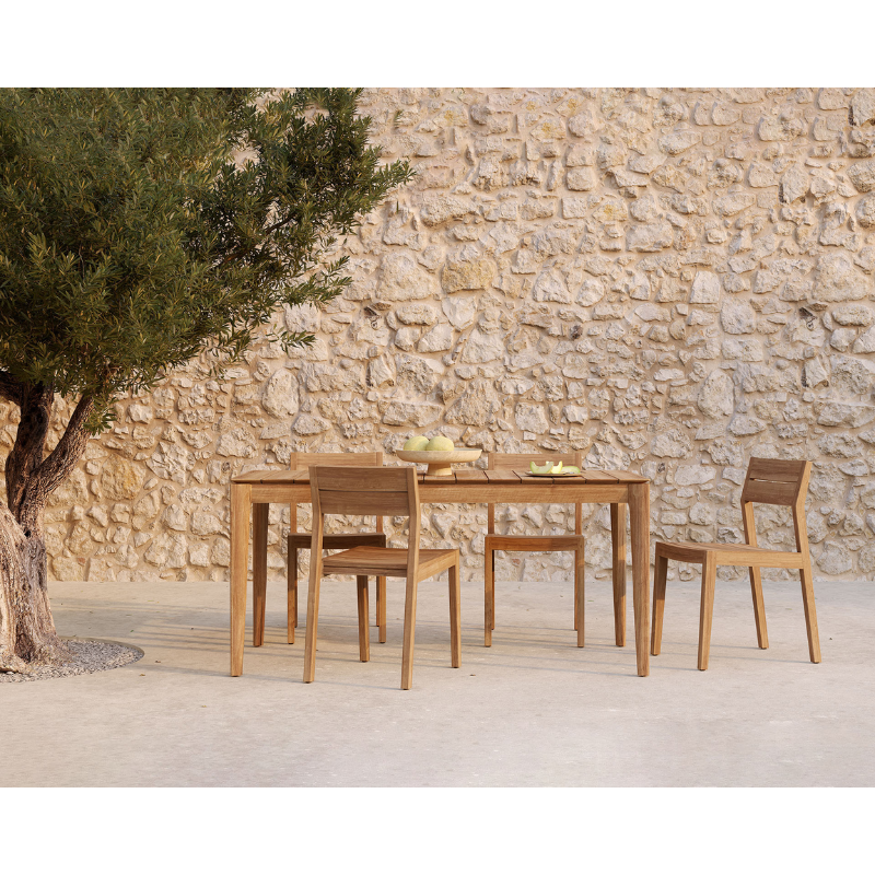 The EX 1 Outdoor Dining Chair from Ethnicraft within a courtyard next to a tree, with fruit on top of the table.