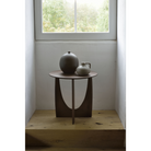 The Geometric Side Table from Ethnicraft underneath a window.