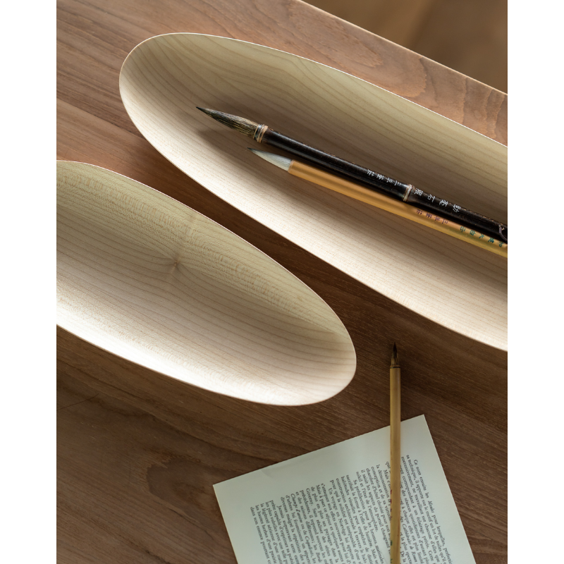 The Thin Oval Boards Set from Ethnicraft in a home office, holding pens and pencils.