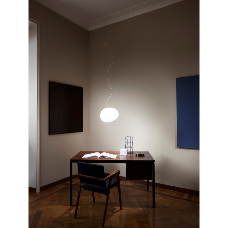 The Gregg Suspension light suspended from the ceiling above a desk for work.