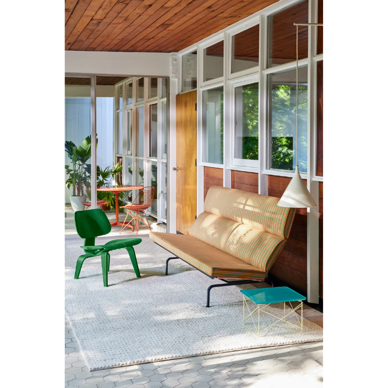 The Eames Sofa Compact from Herman Miller, designed by Herman Miller x HAY in a lifestyle photograph with the plywood lounge chair and low table. The Eames Dining Table and Wire Chair can also be seen in the background.