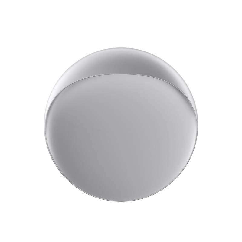 The Flindt Wall is distinguished by a light egress from an opening in the top that emits light down the front of the fixture, creating a subtle, glowing ring of reflected light on the transition between the concave and convex shapes. The oval shape is lifted off the mounting surface, giving the fixture a floating appearance.