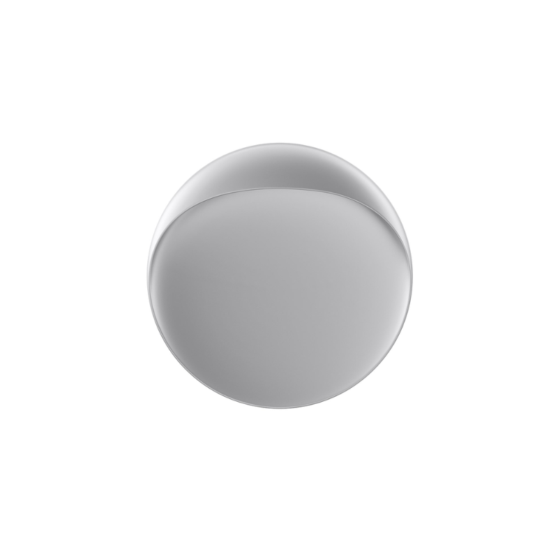 The Flindt Wall is distinguished by a light egress from an opening in the top that emits light down the front of the fixture, creating a subtle, glowing ring of reflected light on the transition between the concave and convex shapes. The oval shape is lifted off the mounting surface, giving the fixture a floating appearance.