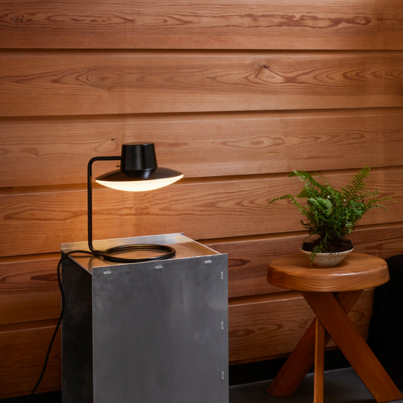 The AJ Oxford Table Lamp emits a pleasant downwardly directed light, which harmoniously illuminates the surface below it through the soft transparency of its triple-layered hand-blown opal glass. In the variant without the top metal shade, the milky opal-glass shade provides further glow to form an alluring halo around the fixture.