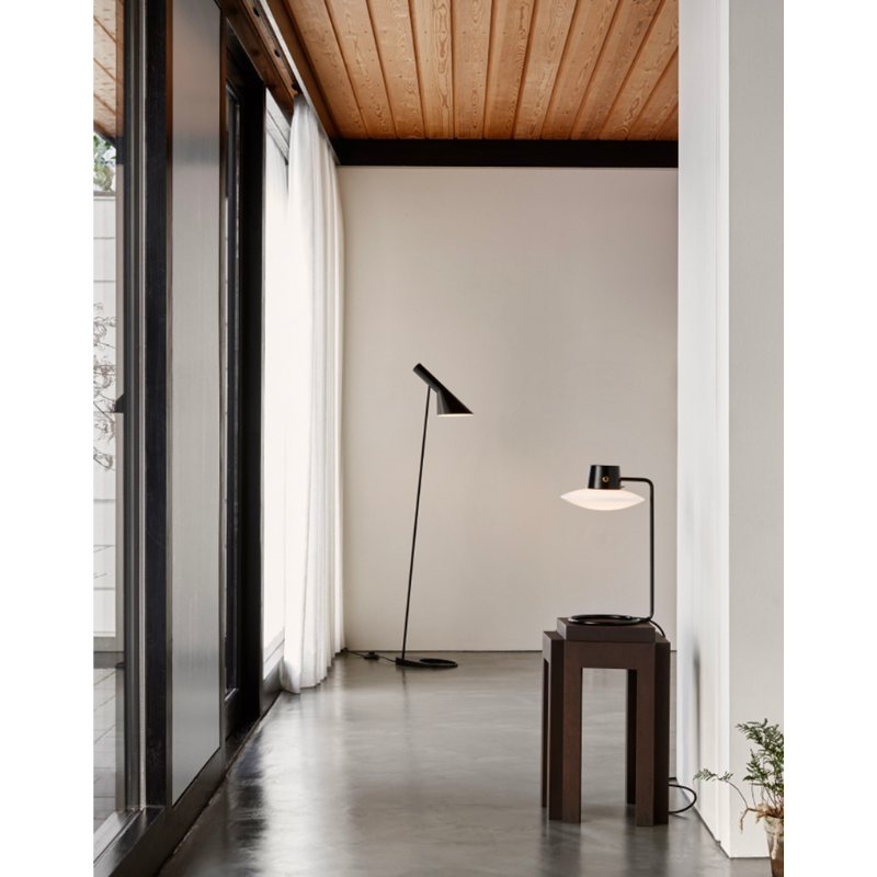 The AJ Oxford Table Lamp emits a pleasant downwardly directed light, which harmoniously illuminates the surface below it through the soft transparency of its triple-layered hand-blown opal glass. In the variant without the top metal shade, the milky opal-glass shade provides further glow to form an alluring halo around the fixture.