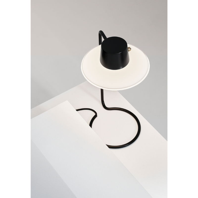 The AJ Oxford Table Lamp emits a pleasant downwardly directed light, which harmoniously illuminates the surface below it through the soft transparency of its triple-layered hand-blown opal glass. In the variant without the top metal shade, the milky opal-glass shade provides further glow to form an alluring halo around the fixture.