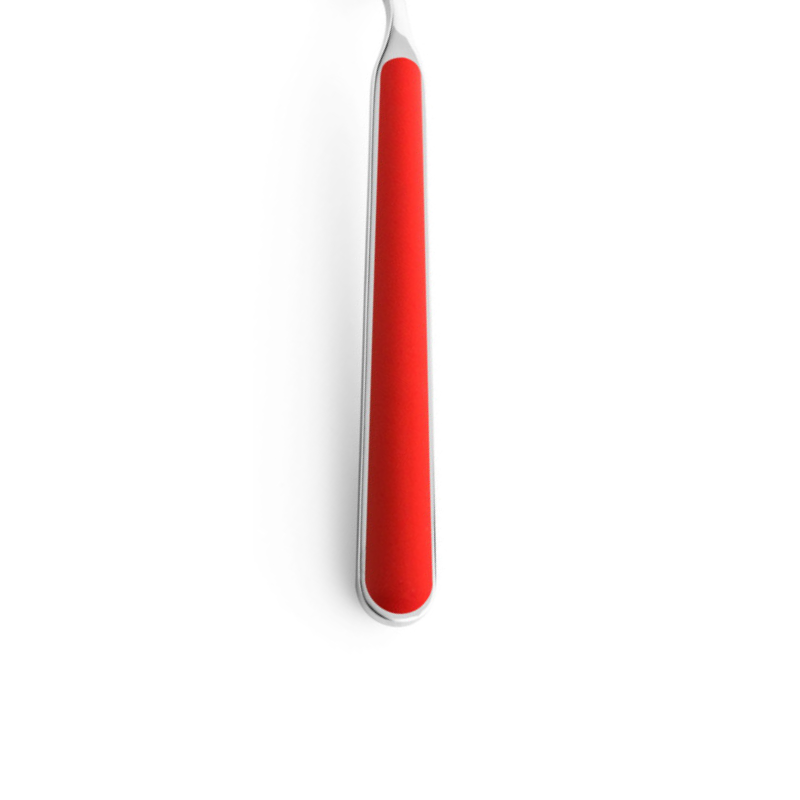 The handle of the Fantasia Salad Serving Fork from Mepra in new coral.