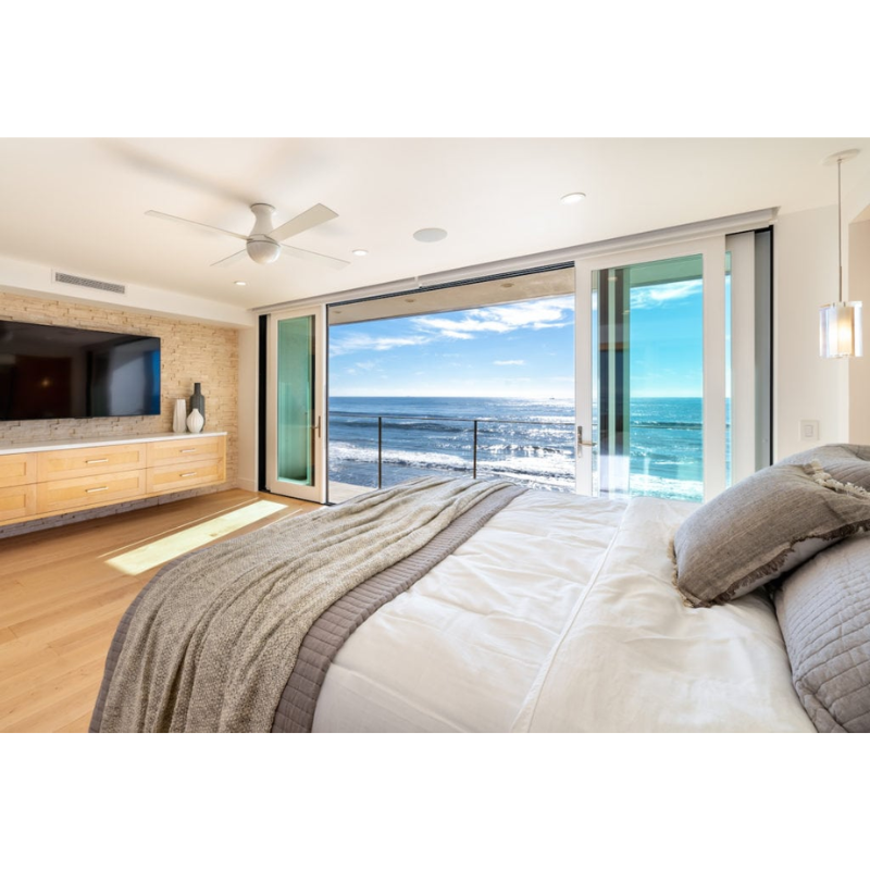 The Ball Flush ceiling fan from Modern Fan Co. with a 52" blade with a gloss white body with white color blades in a master bedroom next to the ocean.