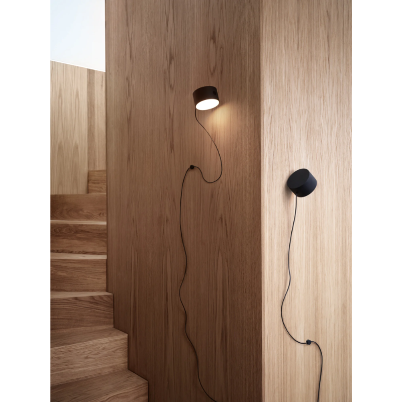 The Post Wall Lamp from Muuto in a hallway illuminating a staircase.