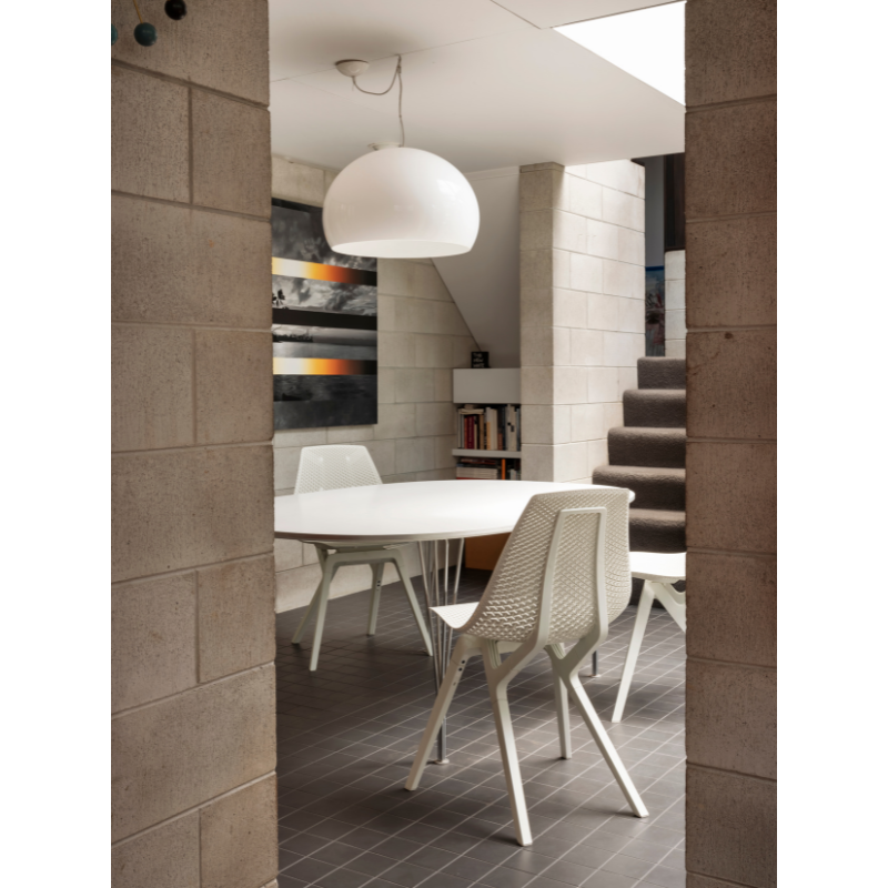 Several Noho Move Chairs in cloud color around a table below a light.