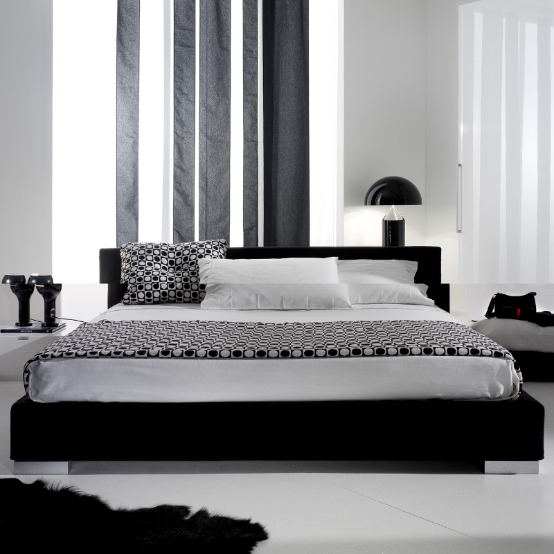 This is the Atollo Metal Table Lamp from Oluce in Black within a bedroom setting.