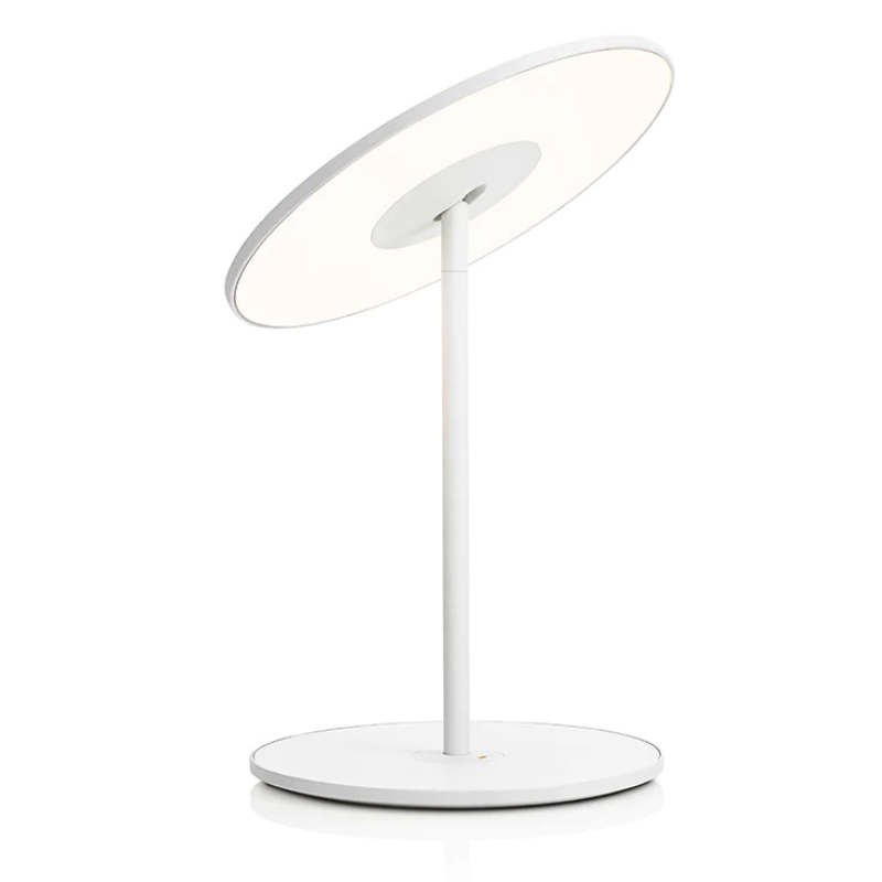 The Circa Table light from Pablo Designs that features an integrated USB charging port, 45° shade tilt, and 360° rotation in white.