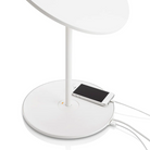 The Circa Table light from Pablo Designs in white, being used to charge a phone through the USB port.