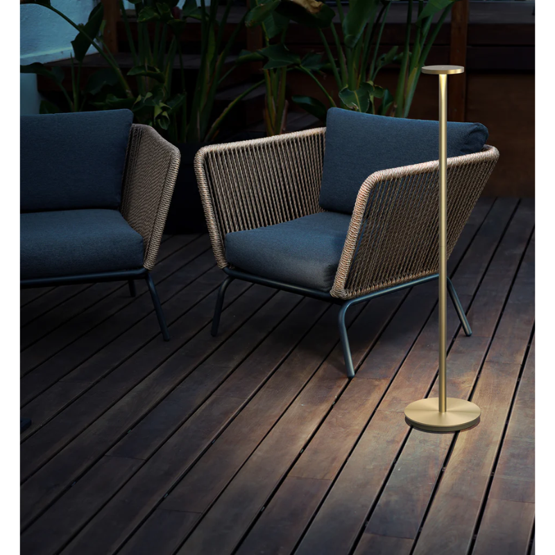 The portable light, Luci Floor from Pablo Designs outdoors next to a seat.