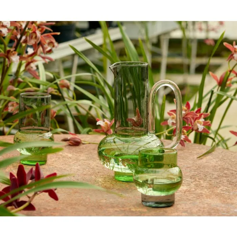 The Bump Jug in green by Tom Dixon in a garden with the Bump Short and Tall Glasses.