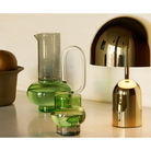 The Bump Jug in green by Tom Dixon with a lamp and a Bump Short Glass.