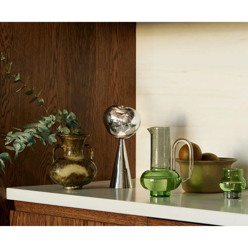 The Bump Short Glasses Green (Set of 2) from Tom Dixon on a counter in a living room.