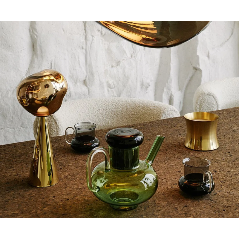The Bump Tea Pot in Green by Tom Dixon in a living space with the Bump Tea Cups in black and Melt portable light.