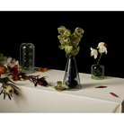 The Bump Vase Cone Black from Tom Dixon being used on a covered tabletop with flowers.