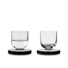 Two Puck Shot Glasses from Tom Dixon, one empty, and one half full.