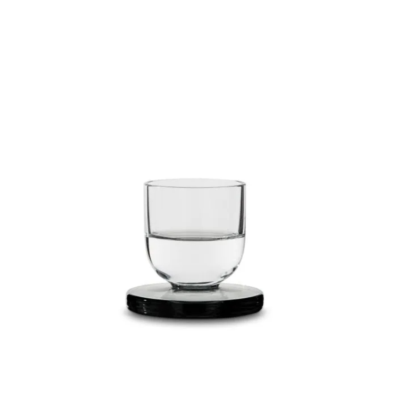 A Puck Shot Glass from Tom Dixon half filled with a liquor.