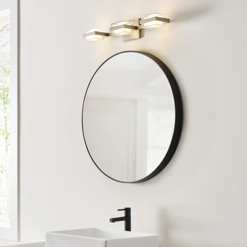 The Kamden 3-Light Bathroom Fixture from Visual Comfort & Co. in a bathroom lifestyle photograph.