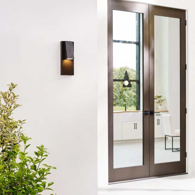 The Peak Outdoor Wall Sconce from Visual Comfort and Co outside beside a doorway entrance.