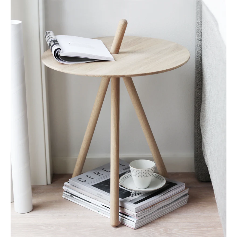 The Come Here Side Table from Woud next to a sofa used as a coffee table.