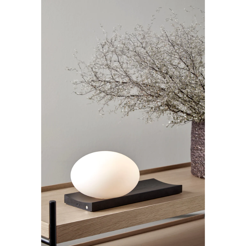 With its portable character, the versatile piece functions as a dynamic table and wall lamp. At the same time, its dimmable feature allows you to change the mood and intensity of the light to suit the specific setting. Place it on a desk, use the tray for your pieces of jewelry or hang it on the wall to provide an inviting light with no need for an electrical supply.