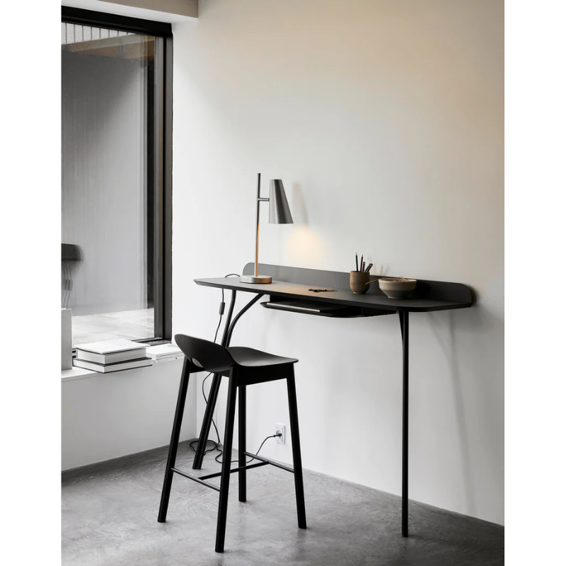 A lifestyle shot of the high Tree Console Table in charcoal from Woud being used as a desk within an office.