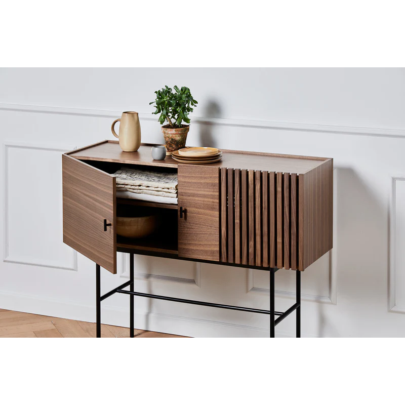 The small Array Sideboard from Woud in walnut, opened up revealing textiles and a bowl.