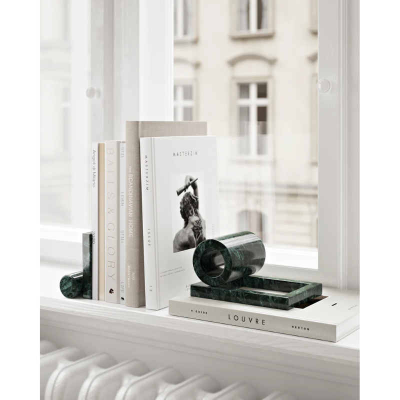 The Booknd from Woud, a solid marble bookend, on a windowsill in a living room.