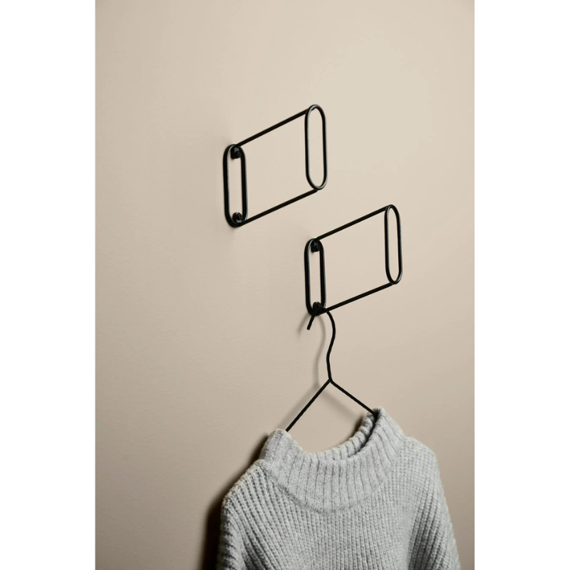 The Eileen Hook from Woud being used to hold up clothes in an entryway lifestyle photograph.