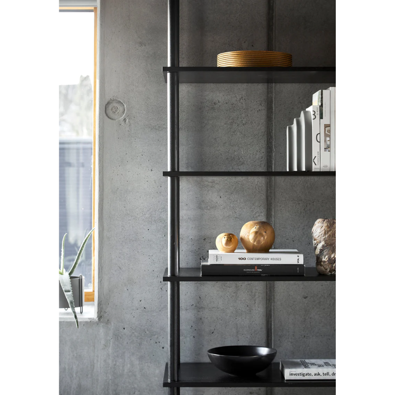 The Hibo Hippopotamus from Woud, made from solid oak sitting on a bookshelf in a living room.