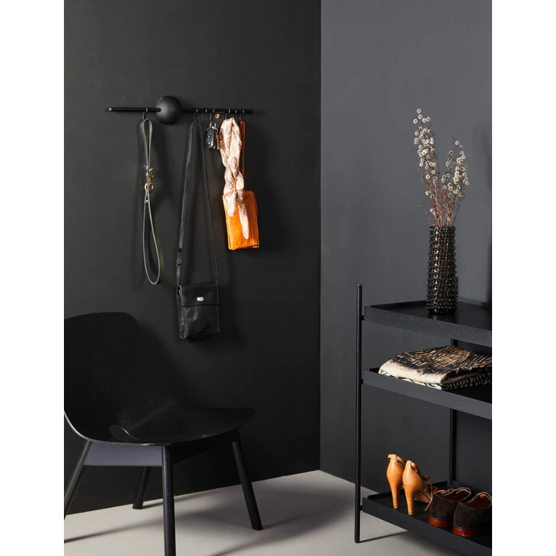 The Hoop Rack from Woud in black being used in a bedroom.