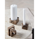 The solid marble Jeu De Dés 1 Candle Holder from Woud The solid marble Jeu De Dés 1 Candle Holder from Woud with a taper light, and two other styles of candle holder in brown.