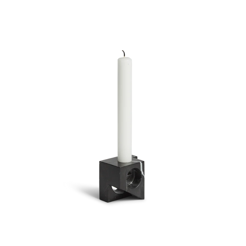 A photograph of the solid marble Jeu De Dés 2 Candle Holder by Woud in black with a taper candle.