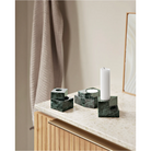 A photograph of the solid marble Jeu De Dés 2 Candle Holder by Woud in green on top of a counter.